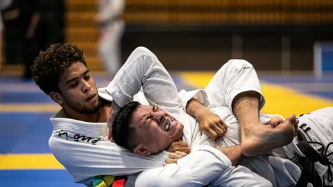 Two jiu-jitsu athletes grappling on the mat